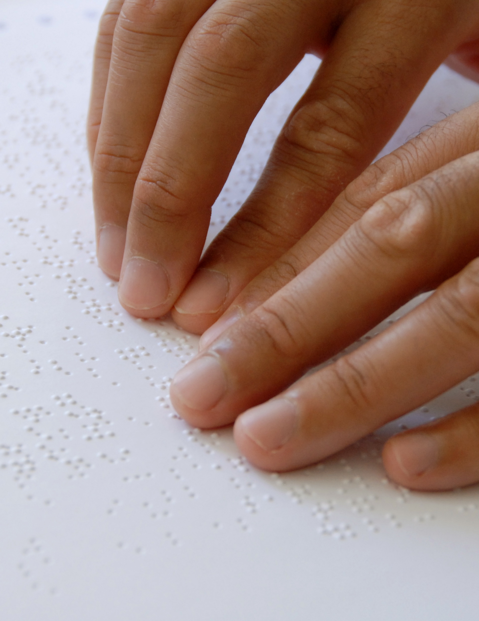 Fotografie: Zwei Hände beim Lesen von Blindenschrift